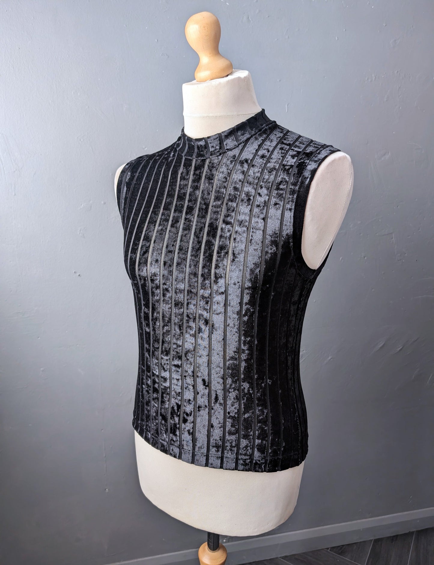 Black sleeveless velvet top on a mannequin against a gray background