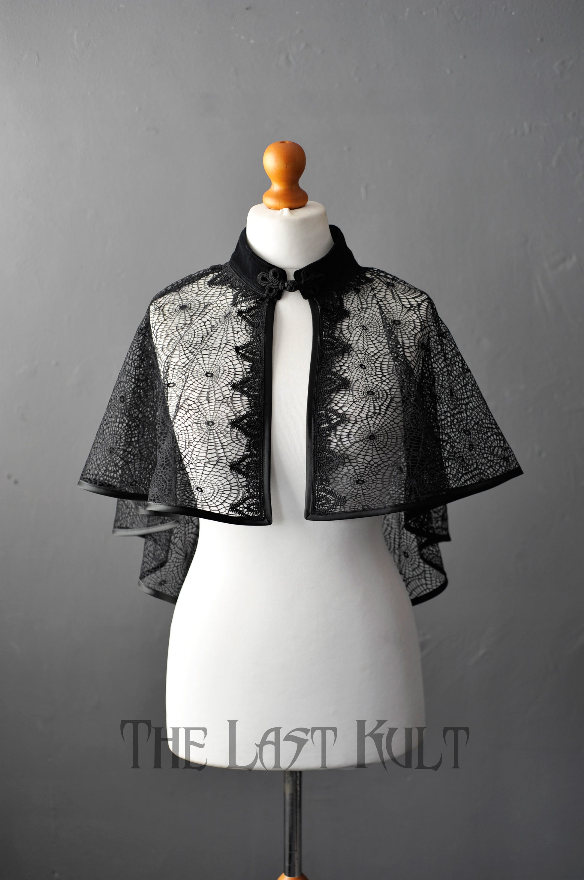 Black cobweb lace capelet on a mannequin against a gray background with 'The Last Kult' branding.