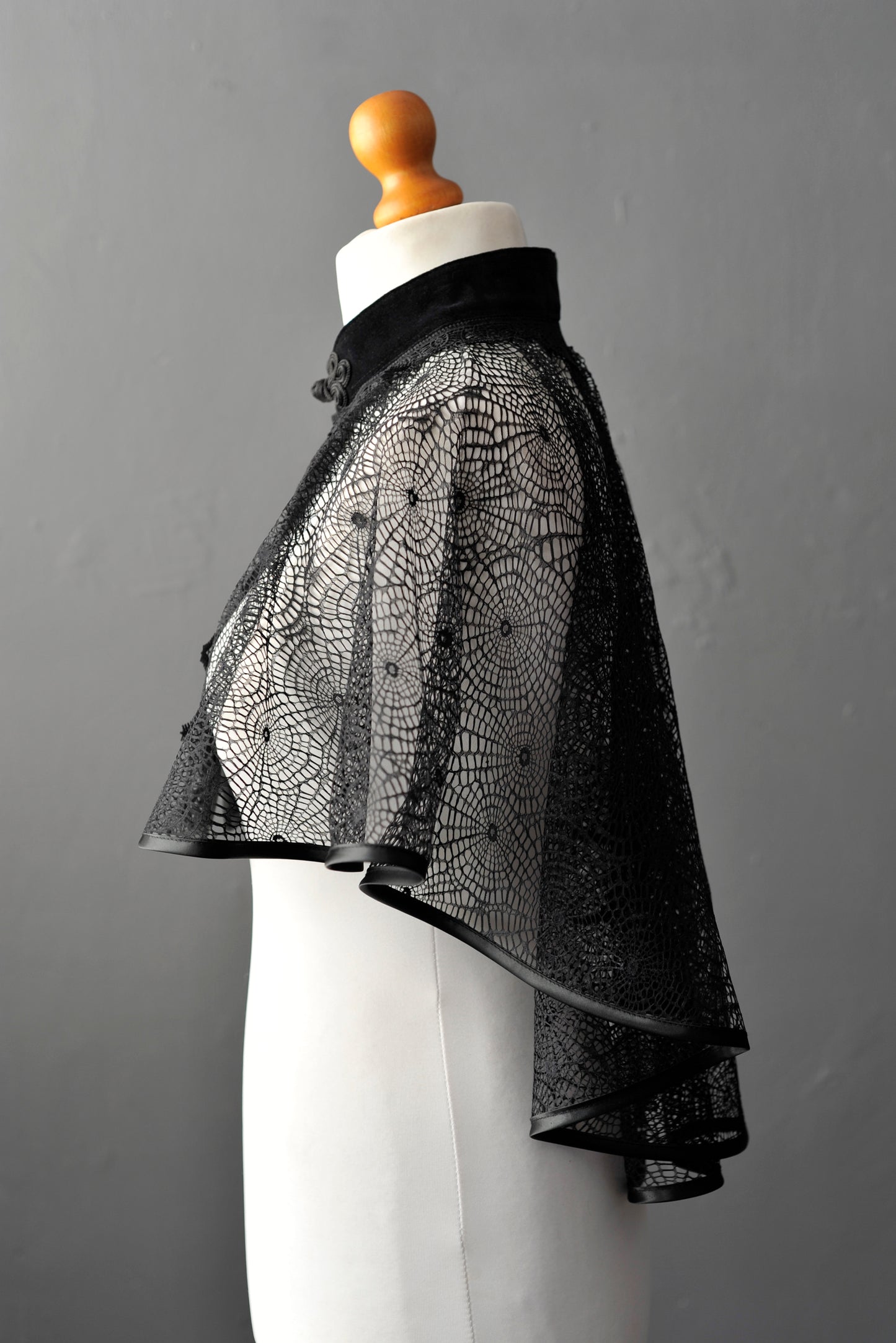 Black lace cape on a mannequin against a gray background